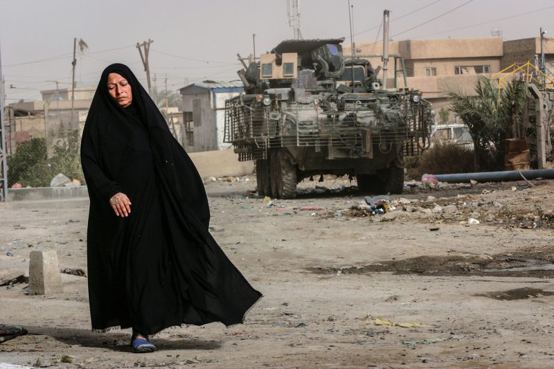 Eine Irakerin passiert im südlichen Teil Bagdads einen Stryker Radschützenpanzer der US-Armee. (c) Simon Klingert