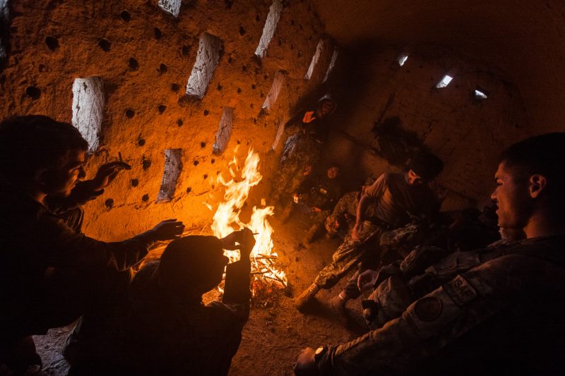 Militäroperation in Kandahar: Amerikanische und afghanische Soldaten wärmen sich in einem verlassenen Bauernhaus an einem Feuer. (c) Simon Klingert