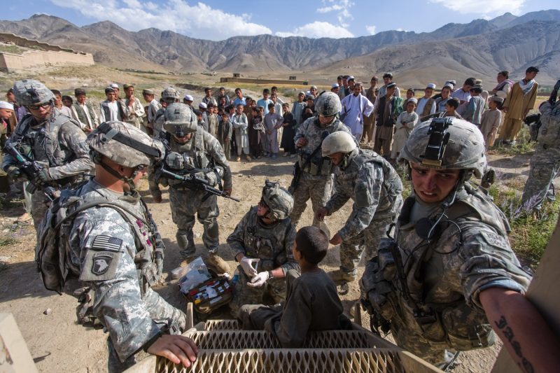 Ein Sanitäter der US-Armee versorgt den verletzten Fuß eines jungen Afghanen. (c) Simon Klingert