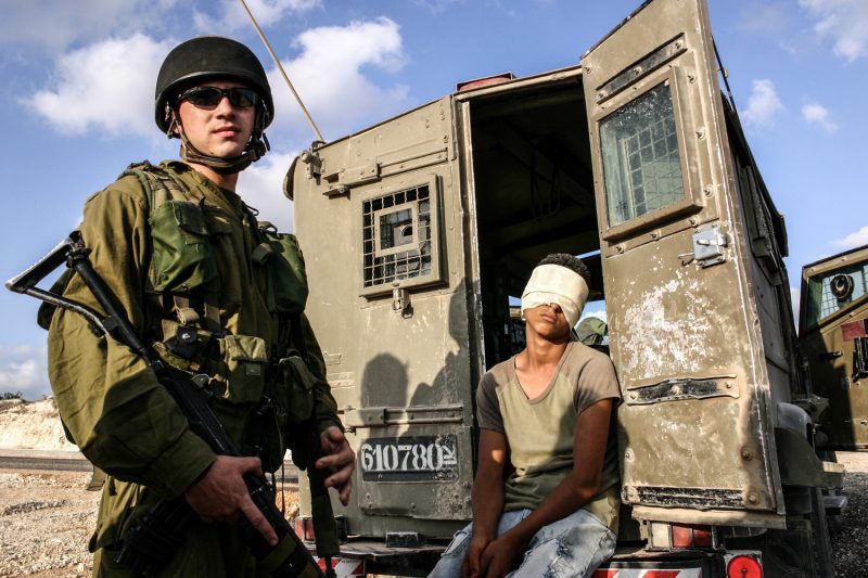 Ein Soldat der israelischen Armee bewacht im Westjordanland einen festgenommenen jungen Palästinenser. (c) Simon Klingert